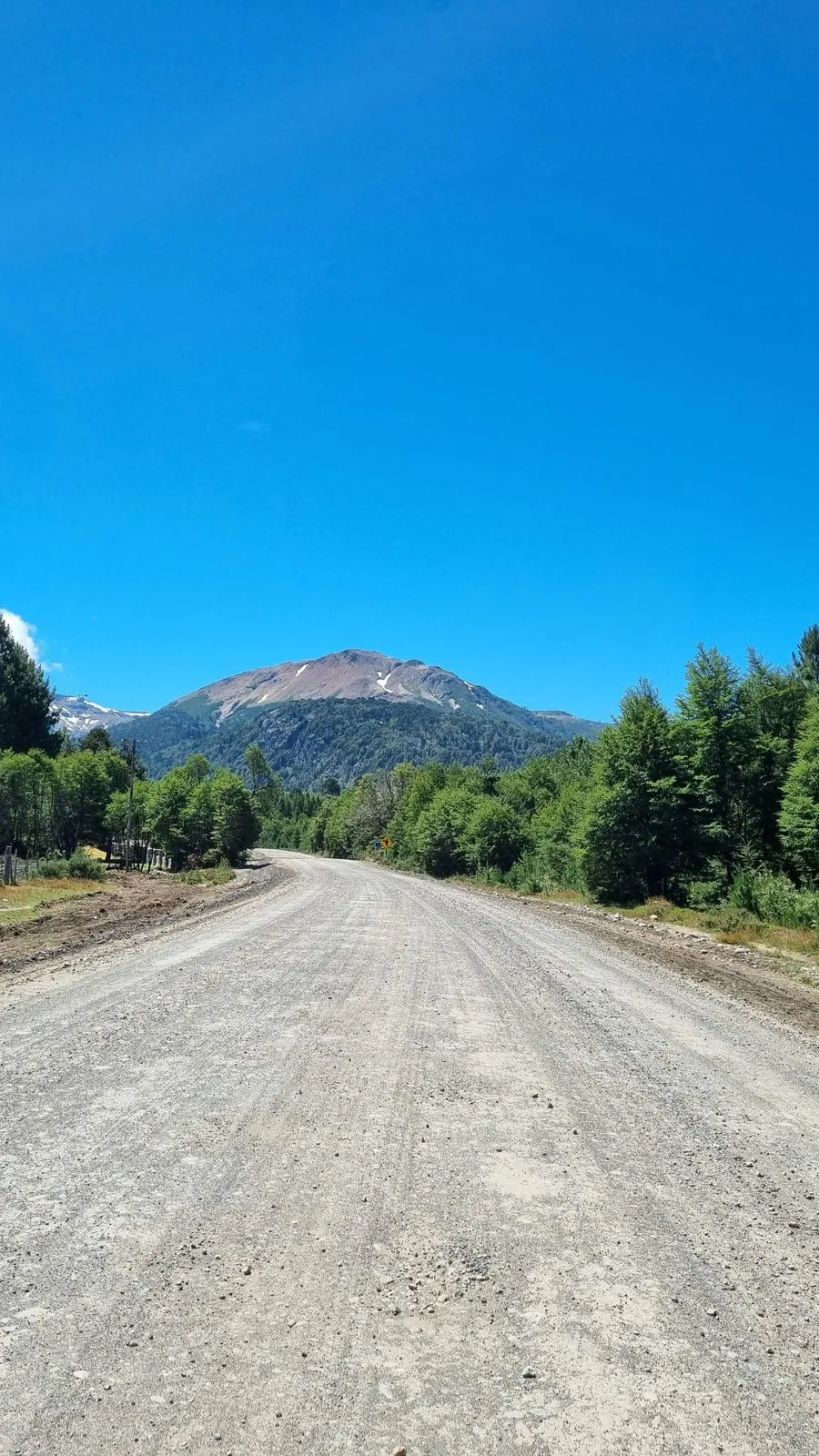 Camino de ripio rumbo a Villa Pehuenia, con la cordillera de fondo