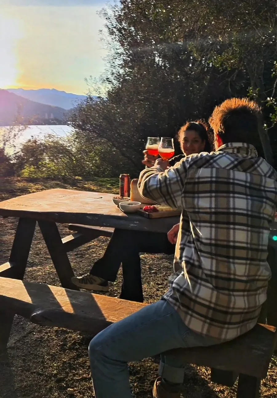 Pareja brindando al atardecer con vista al lago en Villa Pehuenia