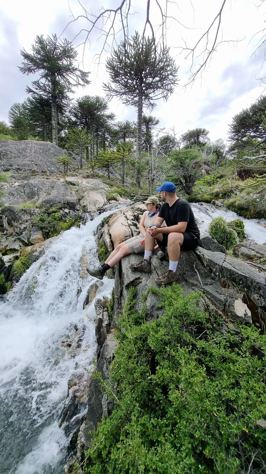 Pareja descansando junto a una cascada en un trekking cerca de Villa Pehuenia